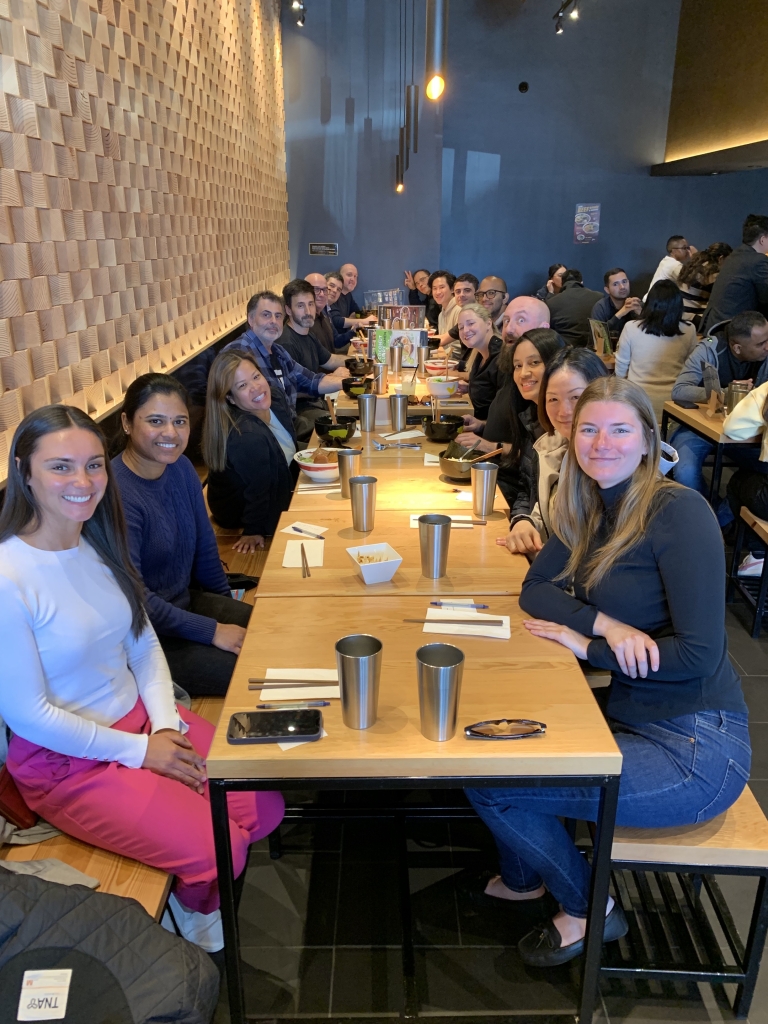 Tarrison's staff sits smiling at a long wooden table